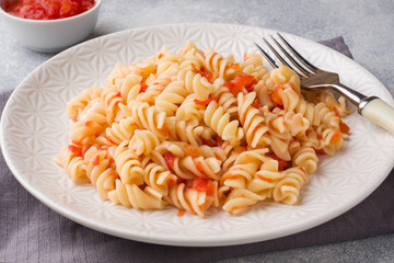 Spiral pasta mixed with cherry tomatoes and tomato sauce on a plate.
