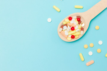 medicine pills, tablets and capsules on wooden spoon