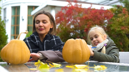 Fototapeta premium Happy mother and daughter carving pumpkin jack-o-lantern for Halloween party