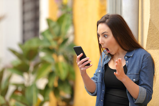 Surprised woman checking online news on phone