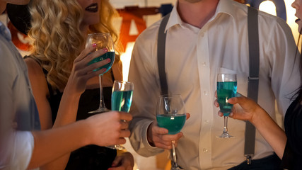 Friends celebrating Halloween and drinking blue color beverage, trick or treat