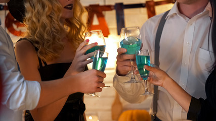 Young people in costumes talking, drinking and having fun at Halloween party