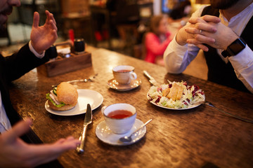 High angle closeup of two business people enjoying lunch in cafe, copy space