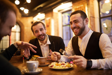 Group of cheerful business people enjoying food and conversation in cafe, copy space