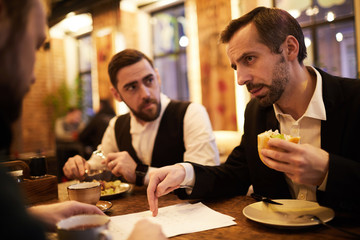 Group of successful business people discussing work during dinner in cafe, copy space