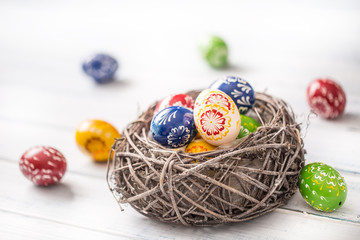 Close-up multicolored easter eggs in basket on wooden table