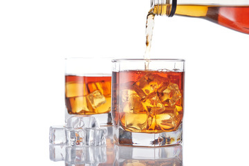 Bottle of whisky and two glasses. Pouring