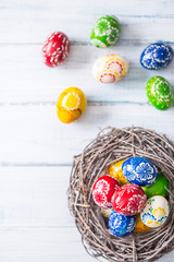 Close-up multicolored easter eggs in basket on wooden table