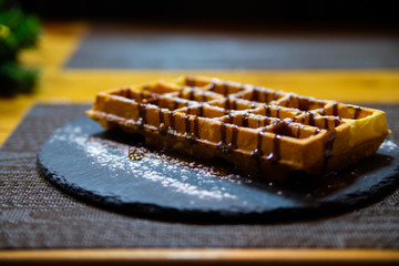 Belgian waffle with chocolate syrup and powdered sugar
