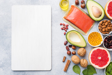 Healthy food antioxidant products: fish and avocado, nuts and fish oil, grapefruit spinach and oil on a gray concrete background. copy space