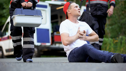 Man suffering pain in chest waiting ambulance crew, heart problems or asthma