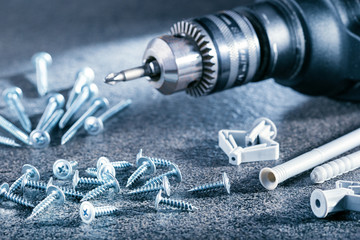  Building, repairing and home maintenance concept. Electric screwdriver and various screws on gray...