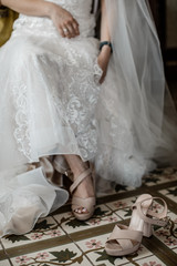 Fototapeta na wymiar A bride is taking off her shoes. She is wearing the white wedding dress.