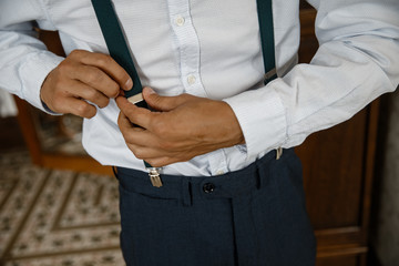 A man is adjusting his suspenders closeup.