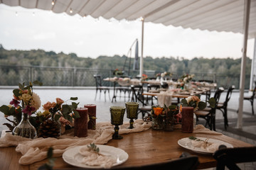 A lot of the decorations and some empty plates are standing on the table. Restauraunt terrace at the background.