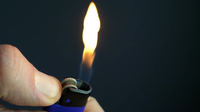 Close up ignite of cigarette lighter in the hand with flame.