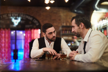 Portrait of two business people drinking whiskey in restaurant after work, copy space