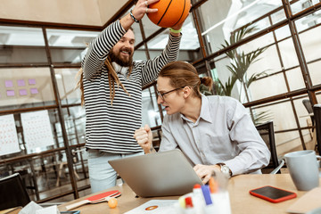 Delighted happy man distracting his colleague from work