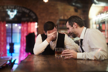 Portrait of two drunk businesspeople sitting at bar counter after work, copy space