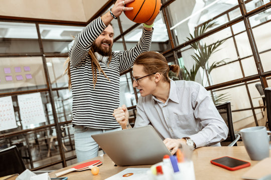 Delighted happy man distracting his colleague from work
