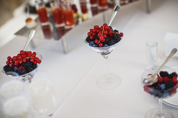 Three cocktail glasses filled with some berries are standing on the white table.