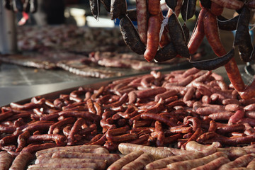 Different kinds of fresh spanish sausages hanging in bunches on the marketplace. Soft focus.9