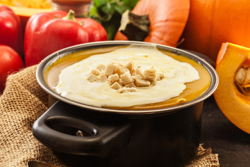 Pumpkin soup with cream and croutons in a pot