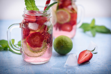 Close up view on lime and strawberry detox drink in glass mason jars on a blue background 8