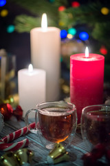 A couple of burning candles and glass cups of tea. Still life composition with christmass decoration on rustic background 3
