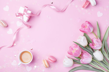 Morning cup of coffee, cake macaron, gift or present box and spring tulip flowers on pink background. Beautiful breakfast for Women day, Mother day. Flat lay.