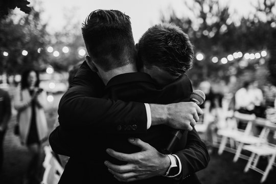 A groom is hugging with a best man. Farewell hug concept.