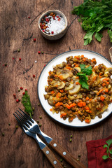 Green lentils with mushrooms and vegetables, old wooden kitchen table background, place for text. Vegetarian meal, vegan food concept. Top view