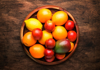 Bright fruits in large tray: oranges, lemons, mango in assortment. View from above