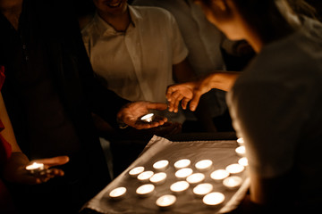 People are holding a candles in their hands. The waiters are handing out the candles to the people.