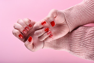 Girl's hands with a red manicure on her nails are isolated on a pink background