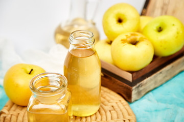 Glass Bottle of apple organic vinegar on blue background.