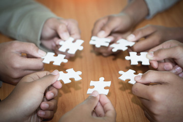 Hands of diverse people assembling jigsaw puzzle, Youth team put pieces together searching for right match, help support in teamwork to find common solution concept, top close up view