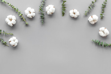 Flowers composition on gray desk with eucalyptus branches and cotton. Flat lay, top view, copy space