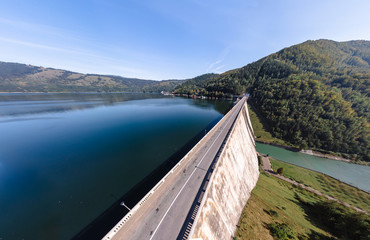 Aerial scenic view of a dam constructed on a beautiful valley in mountains. water storage reservoir. road with beautiful views for travel and holidays. lake Lzvorul Muntelui, Romania.