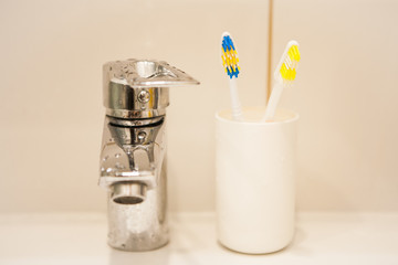 Two toothbrushes in the white plastic cup