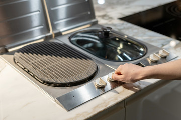 Woman turning on electric kitchen built-in grill