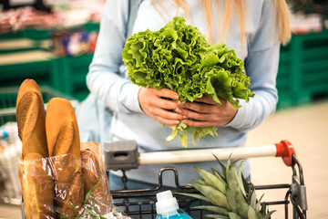 Woman choosing green leafy vegetables in grocery.