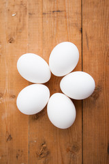 Five white eggs on a wood ground
