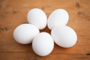 Five white eggs on a wood ground