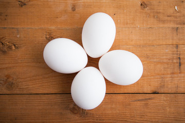 Four white eggs on a wood ground