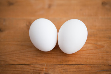 Two white eggs on a wood ground