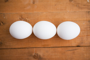 Three white eggs on a wood ground
