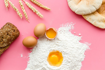 Baking background with eggs, flour and bread on pink table. Top view.