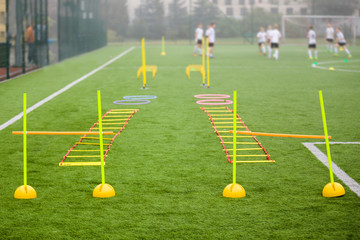 Soccer field with training equipment and fence in background. Junior football team training with...