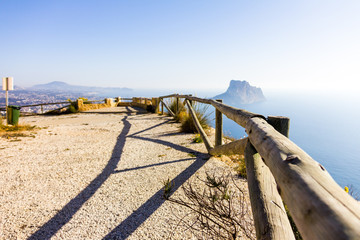 Wooden railing in a mountain path, the viewpoint of Morro de Toix, Penon of Ifach in Calpe is in...